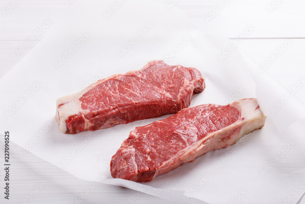 Raw beef striploin steak. Two strip loin steaks on white table. Raw beef striploin steak. Two strip loin steaks on white table.
