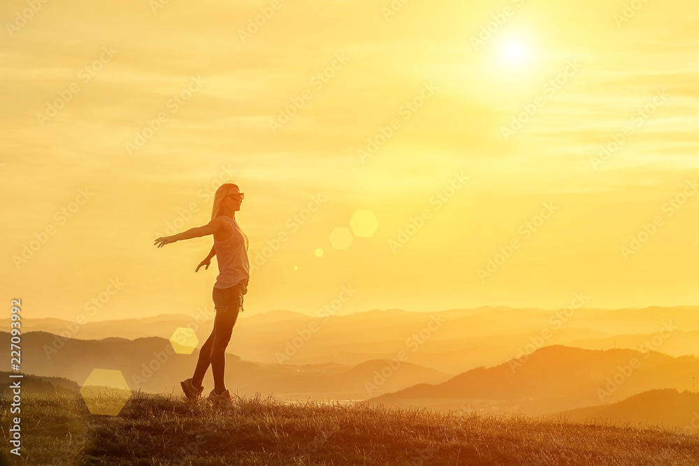 Happy woman with open arms stay on the peak of the mountain clif