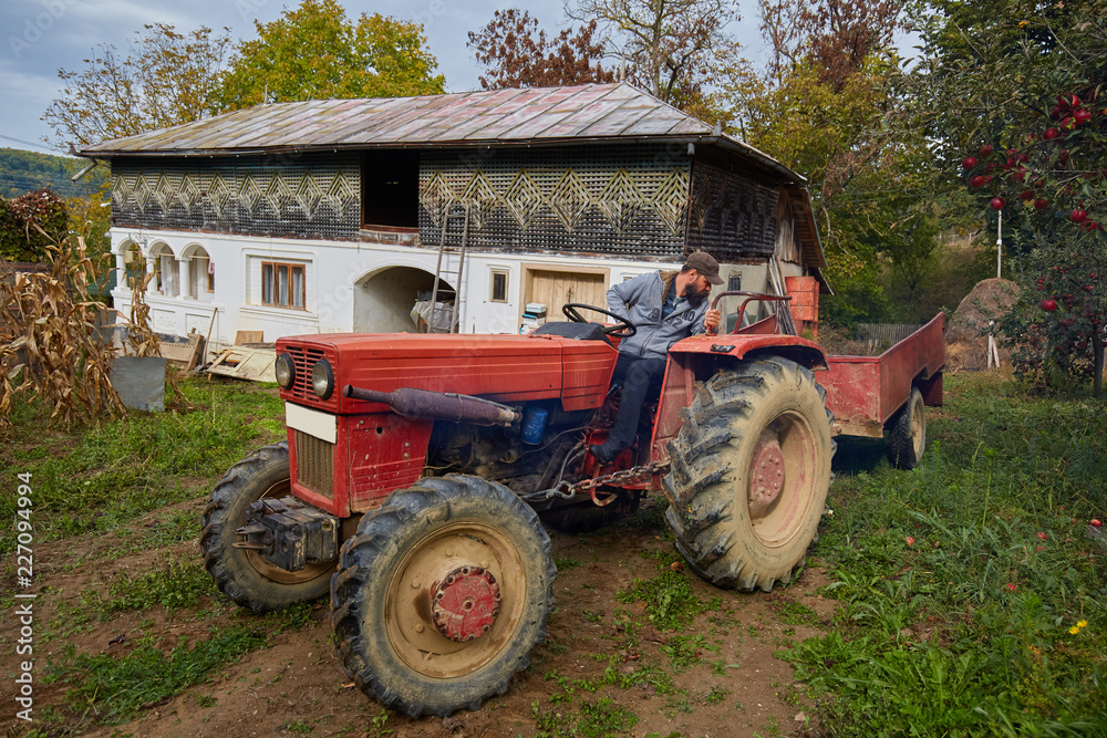 Farmer driving tractor through backyard orchard Farmer driving tractor through backyard orchard