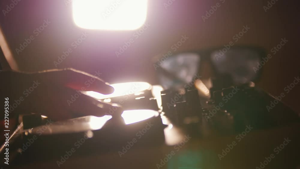 dj takes headphones from front part. mixer under the light wit the sunglasses