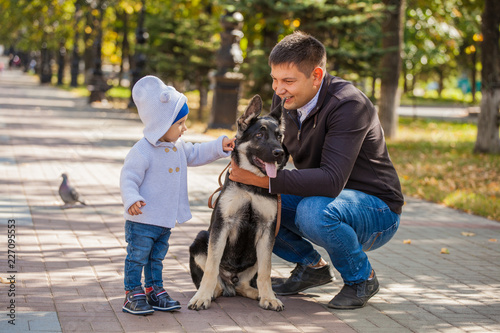 dad and son for a walk in the park with his pet shepherd. The dog loves the child