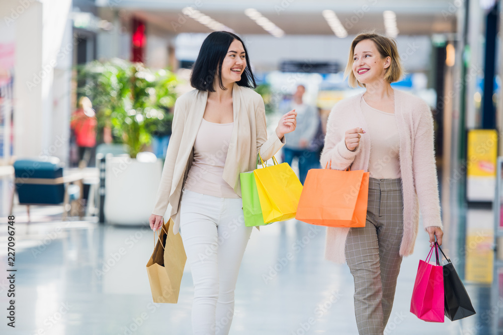 Shopping women talking happy holding shopping bags having fun laughing. Two beautiful young woman girlfriends at mall Shopping women talking happy holding shopping bags having fun laughing. Two beautiful young woman girlfriends at mall