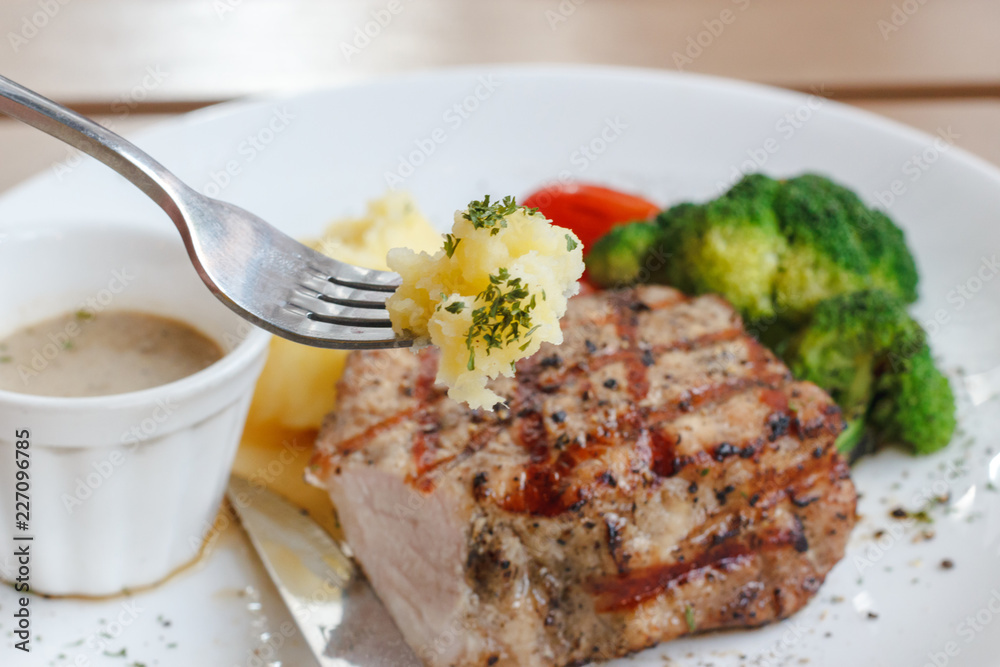 Enjoy eating bite of mash potato with Fork and pork Juicy Steak background