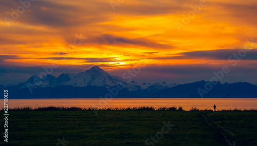 A figure watches the sunset over Mount Illiamna and Cook Inlet in Ninilchik, Alaska photo