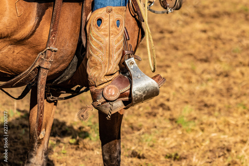 Lovely crafted stirrups and saddle, american cowboy warming up before rodeo performance on new ranch © Edward R