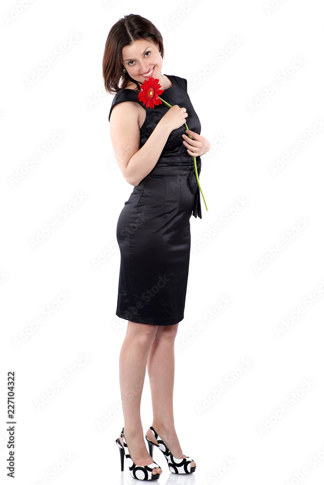 Beautiful young woman in black dress holds gerbera flower in hands, turned the right side and looks in the camera Beautiful young woman in black dress holds gerbera flower in hands, turned the right side and looks in the camera