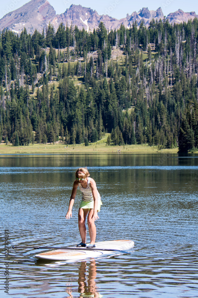 Fototapeta premium Active fit woman on a Stand up paddleboard boating on Todd Lake in the Cascade Lakes area in Bend Oregon on a sunny day