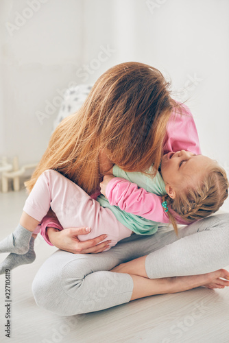 Young mother and her daughter playing in the bedroom