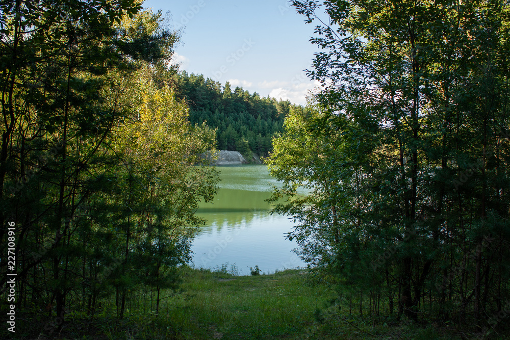 Obraz premium Reflection of forest and white clouds in the blue water of a forest lake. Summer evening. In the vicinity of Grodno. Belarus.