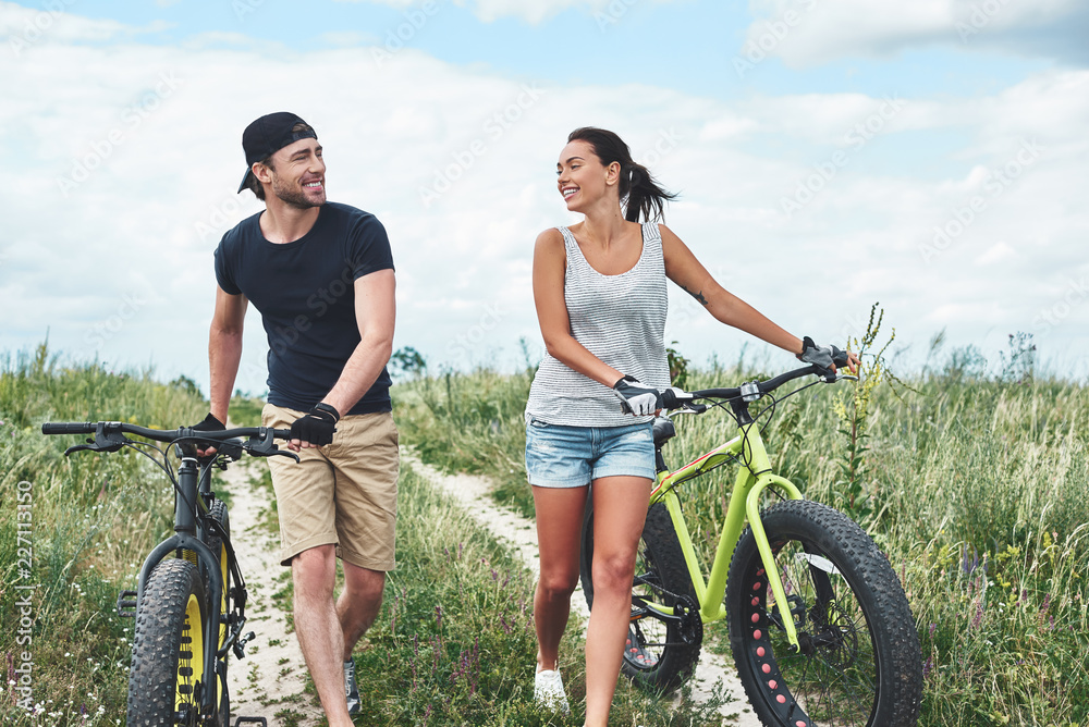 Obraz premium Young couple resting after bike ride in field