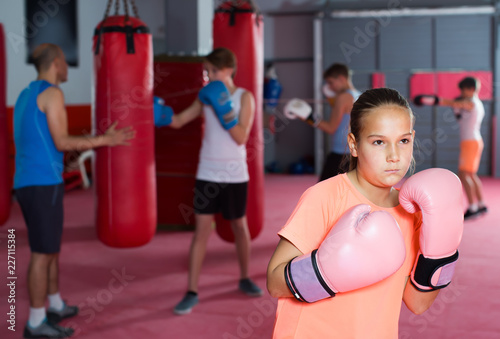 Portrait of positive girl boxer in boxing hall