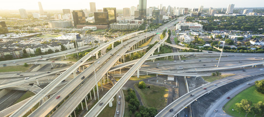 Panorama aerial Interstate I-610 freeway massive intersection and Houston midtown skylines background. Stack interchange, elevated road junction overpass viaduct. Nightly degree view metropolitan area