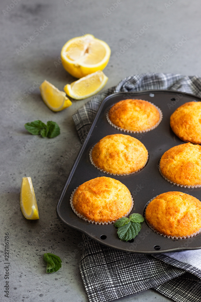 Homemade lemon muffins in black teflon baking dish over grey concrete background. Copy space. Homemade lemon muffins in black teflon baking dish over grey concrete background. Copy space.