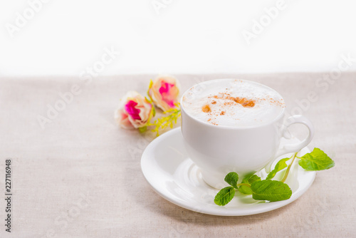 Fototapeta Naklejka Na Ścianę i Meble -  white cup of coffee on a background of scattered flower buds on a white background