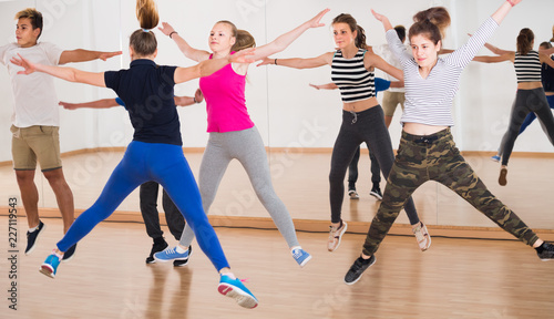 cheerful teenage boys and girls learning in dance hall