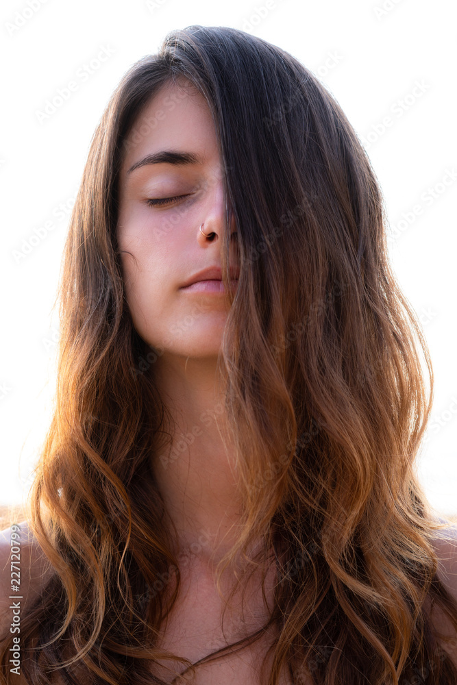 Portrait of a young pretty woman with closed eyes and long wavy hair partially covering her face Portrait of a young pretty woman with closed eyes and long wavy hair partially covering her face