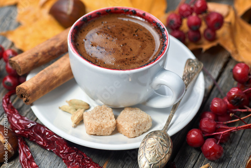 A cup of coffee with chili. Hot steaming cup with coffee. Autumn fall leaves.