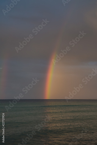 Regenbogen am wolkenverhangenen Himmel am Meer