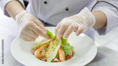 Chef preparing Caesar salad with shrimps