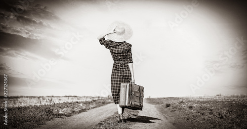 Beautiful girl in plaid dress with bag on countryside. Image in black and white color style
