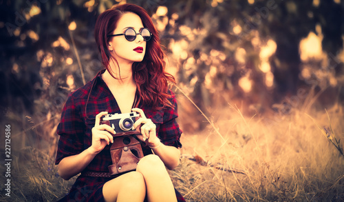 Beautiful girl in plaid dress retro camera and sunglasses at countryside
