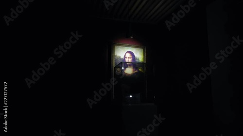 Mona Lisa famous work Leonardo's Da Vinci lights up with flashlight as if a thief wants to make attempt steal art showpiece from museum