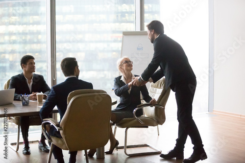 Businesswoman shaking hand of male coach mentor thanking for successful presentation at company meeting, presenter handshaking female boss making good first impression before lecture or seminar