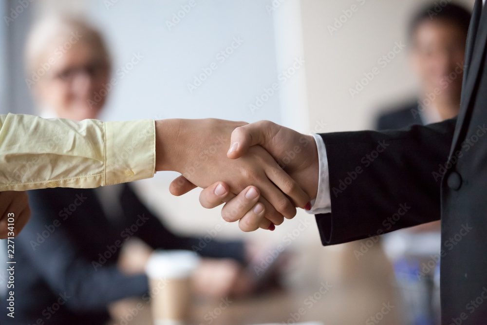 Close up of businessman shaking hand of colleague at office meeting, congratulating with work achievement, boss handshake happy satisfied intern greeting with job promotion. Concept of rewarding