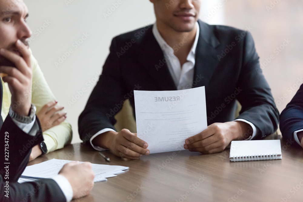 Close up of diverse HR managers consider job applicant during work interview in office, thoughtful recruiters think about candidate, reading resume, listening to qualifications. Hiring concept