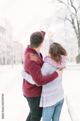 Stylish young couple walking on european winter streets , have fun and hugging. Wearing trendy season outfit. Creamy warm colors.