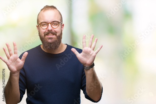 Young caucasian hipster man wearing sunglasses over isolated background showing and pointing up with fingers number ten while smiling confident and happy.