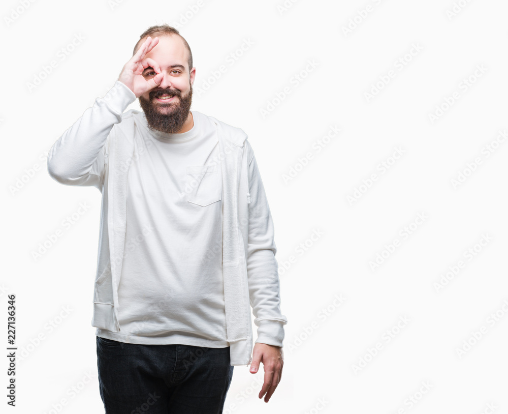 Young caucasian hipster man wearing sport clothes over isolated background doing ok gesture with hand smiling, eye looking through fingers with happy face. Young caucasian hipster man wearing sport clothes over isolated background doing ok gesture with hand smiling, eye looking through fingers with happy face.