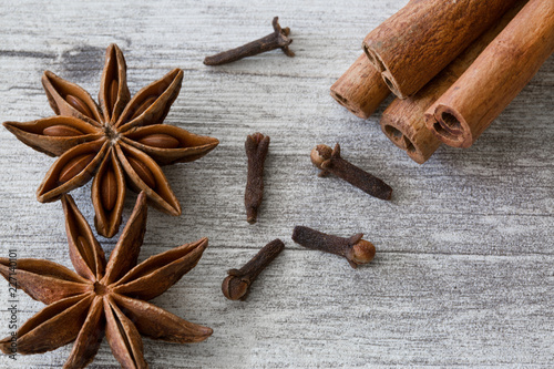 Anise stars, cloves and cinnamon sticks on grey wooden background, close up, macro.