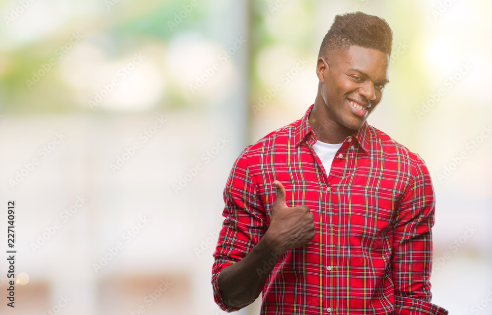 Young african american man over isolated background doing happy thumbs up gesture with hand. Approving expression looking at the camera with showing success.