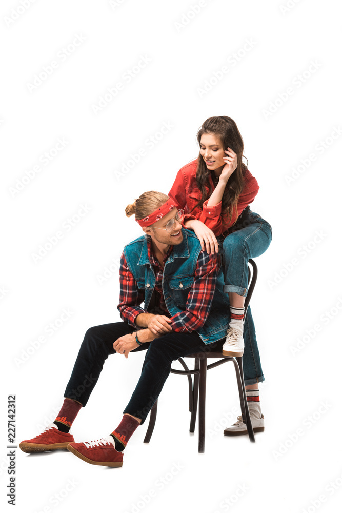 Fototapeta premium cheerful young man sitting on chair while his hipster girl standing behind isolated on white