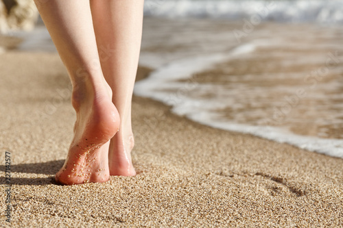 Fototapeta Naklejka Na Ścianę i Meble -  Woman walking on a beautiful sandy beach during sunset, feet close up view