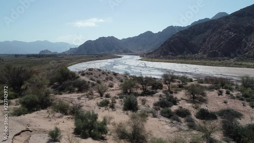 Aerial drone scene of Fiambala meandering river and sand dunes with woods. Dry rocky mountains at background. Cuyo, Catamarca, Argentina. photo