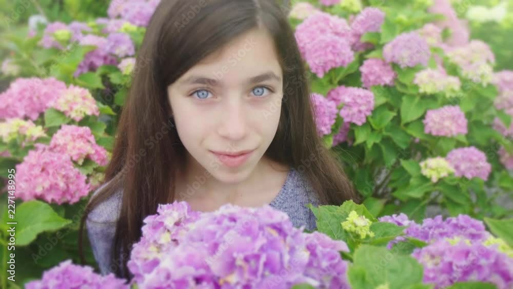 Girl Smells Flower and Looks Up and Smiles. a close up view of a girl in a group of flowers and smells one and looks up at camera and smiles Girl Smells Flower and Looks Up and Smiles. a close up view of a girl in a group of flowers and smells one and looks up at camera and smiles