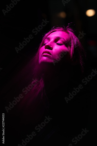 Portrait of girl with reflection of herself looking up on pink lights