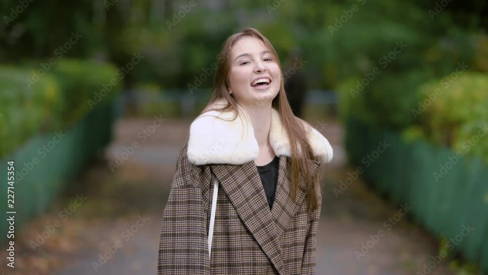 alone pretty brunette woman is standing on a street in alley in park in autumn day, laughing and moving hands alone pretty brunette woman is standing on a street in alley in park in autumn day, laughing and moving hands