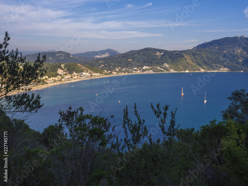 Panoramic view of Agios Georgios Pagon sand beach with green hills and sailing ships at Corfu island, Greece, sunny day blue sky