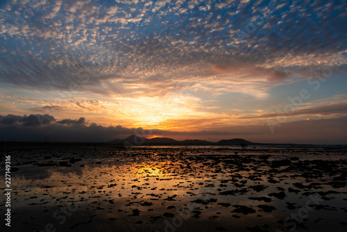 Amazing sunset with pockmarked sky shot on a sandy beach at low tide