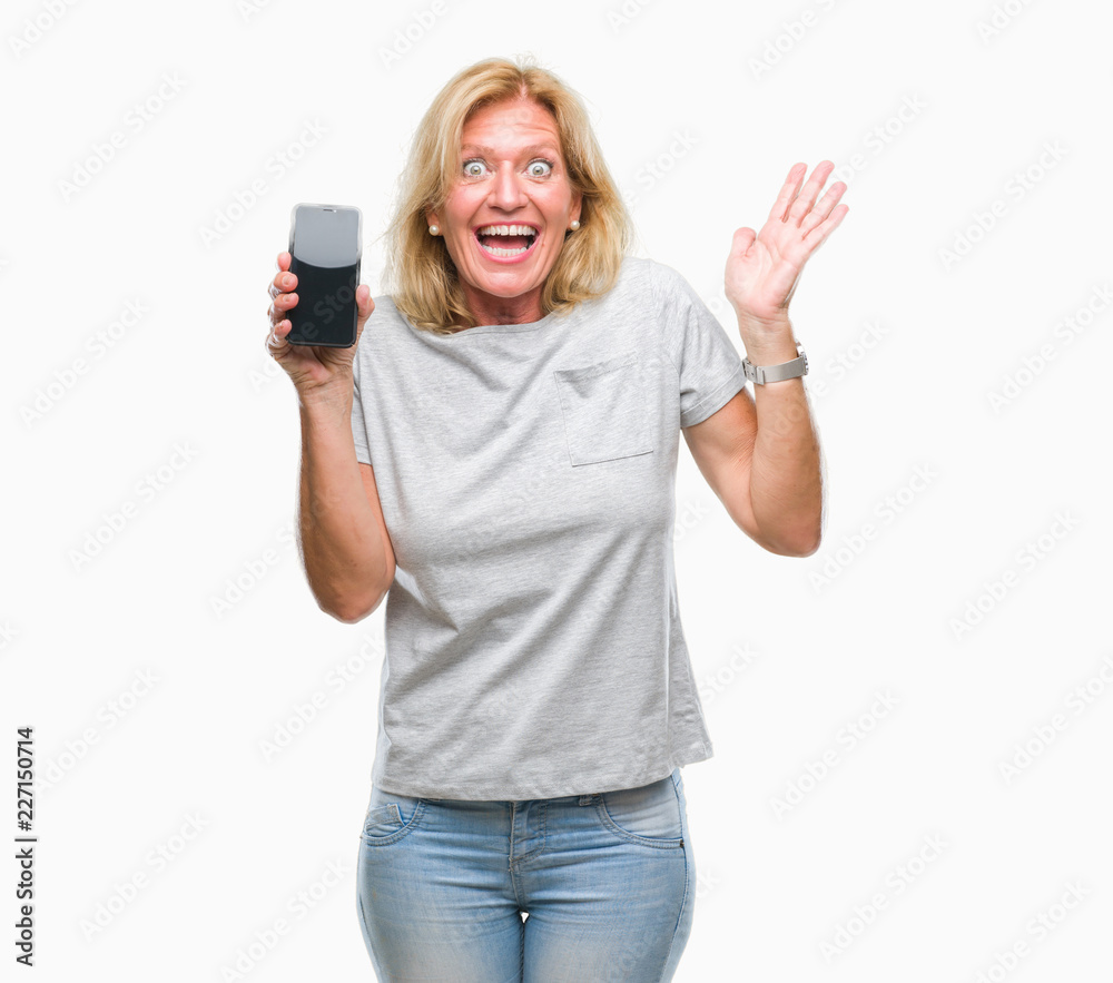 Middle age blonde woman showing blank screen of smartphone over isolated background very happy and excited, winner expression celebrating victory screaming with big smile and raised hands Middle age blonde woman showing blank screen of smartphone over isolated background very happy and excited, winner expression celebrating victory screaming with big smile and raised hands