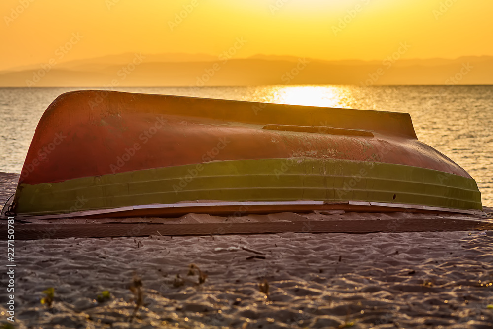 Naklejka premium boat on the shore with sunrise