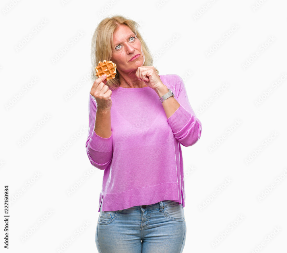 Middle age blonde woman eating sweet waffle over isolated background serious face thinking about question, very confused idea Middle age blonde woman eating sweet waffle over isolated background serious face thinking about question, very confused idea