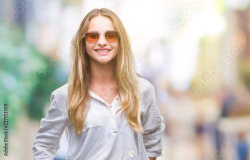 Young beautiful blonde woman wearing sunglasses over isolated background with a happy and cool smile on face. Lucky person. © Krakenimages.com