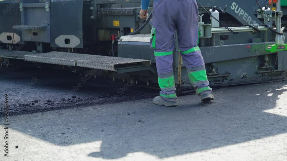 workers are laying asphalt on the road against the background of the machine for paver. Road repair work in process workers are laying asphalt on the road against the background of the machine for paver. Road repair work in process