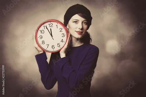 Portrait of beautiful women in blue dress with huge clock on grey background.