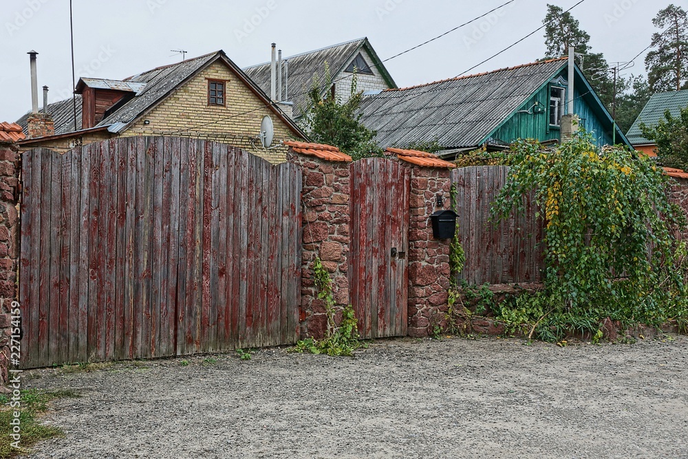 brown wooden gate and part of the fence on rural street brown wooden gate and part of the fence on rural street