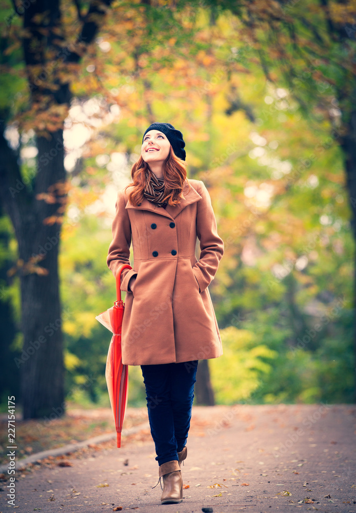 Redhead girl with umbrella in a park. Autumn season Redhead girl with umbrella in a park. Autumn season